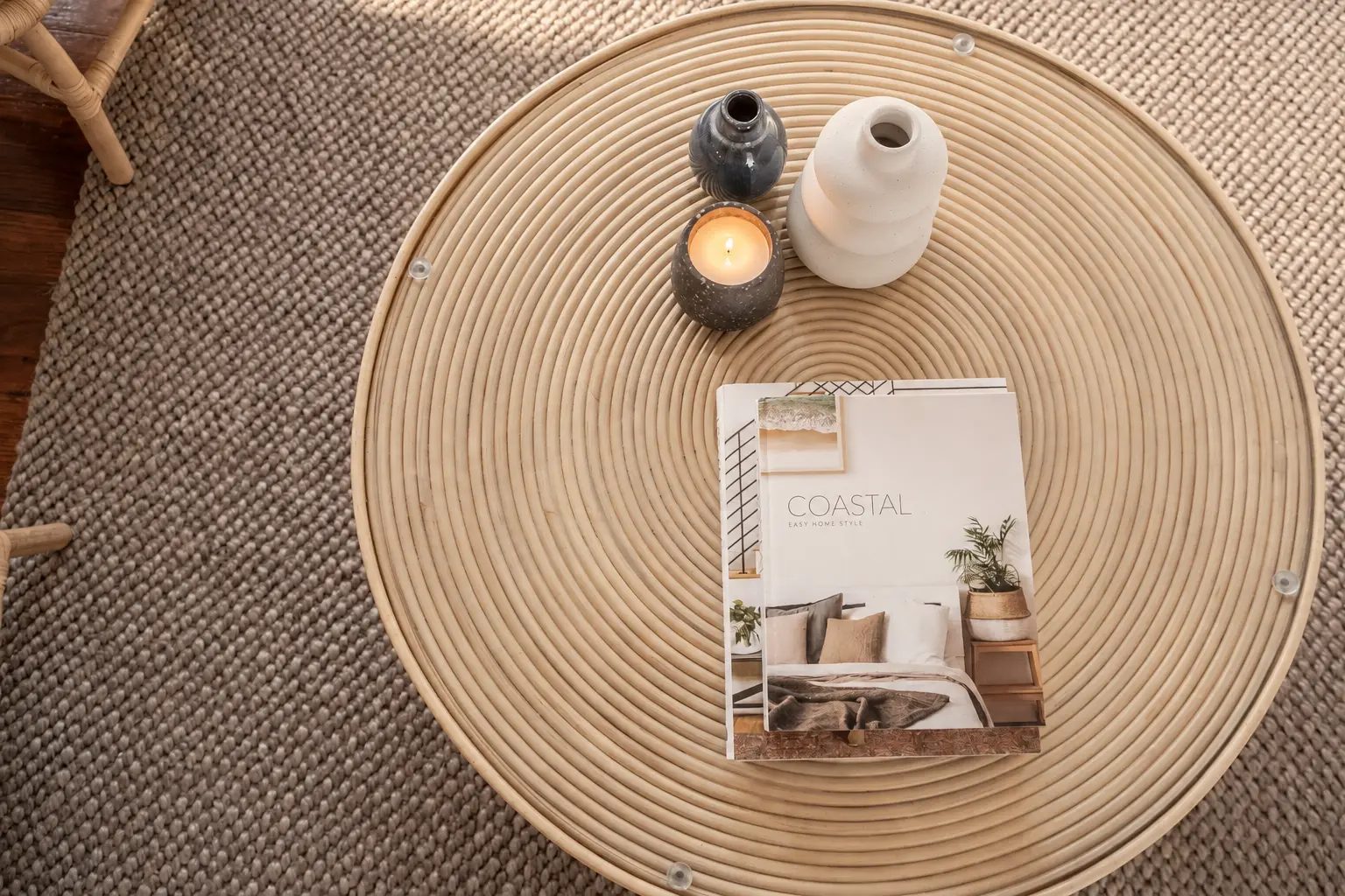 Not Nothing Beach House: round rattan coffee table styled with ceramic vases, a candle and a coastal book