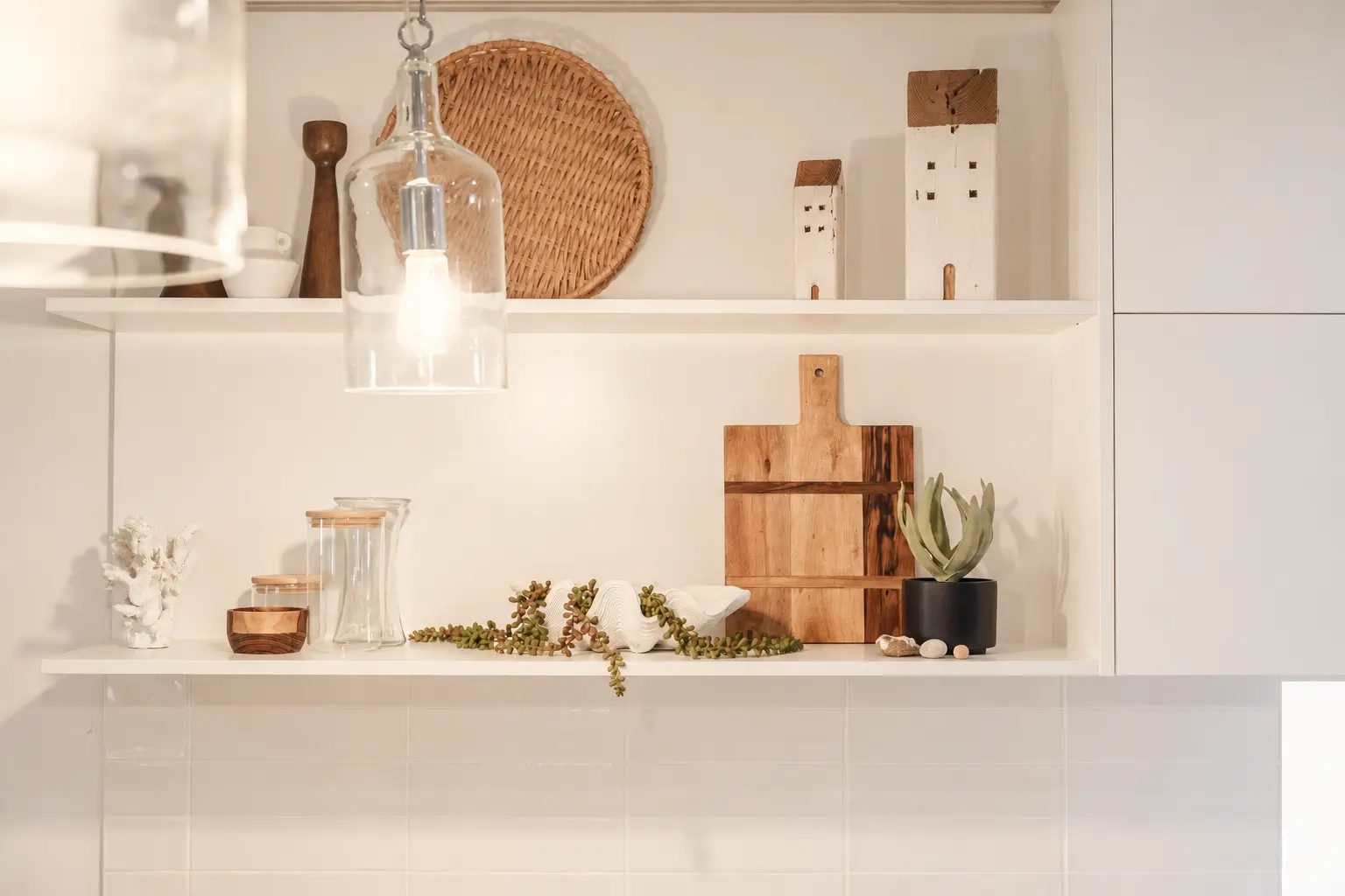 Not Nothing Beach House: open white kitchen shelving styled with timber boards, a woven platter and trailing greenery