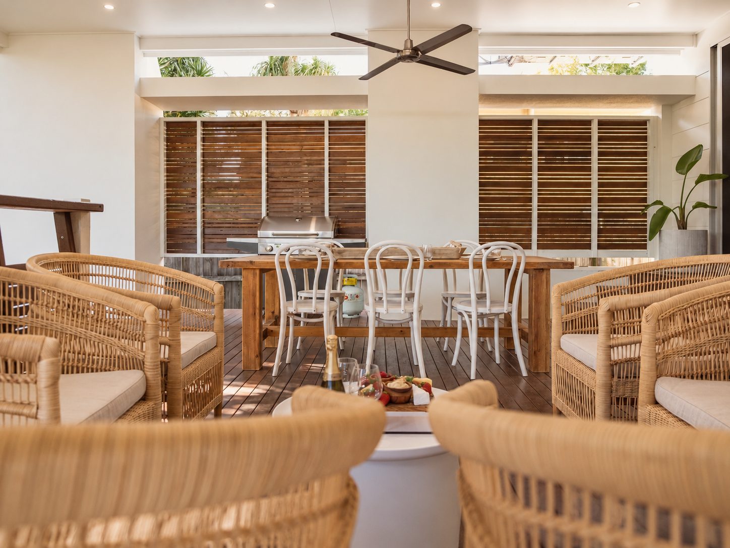 Not Nothing Beach House: alfresco dining with white bentwood chairs, a timber table and slatted timber screens behind rattan chairs