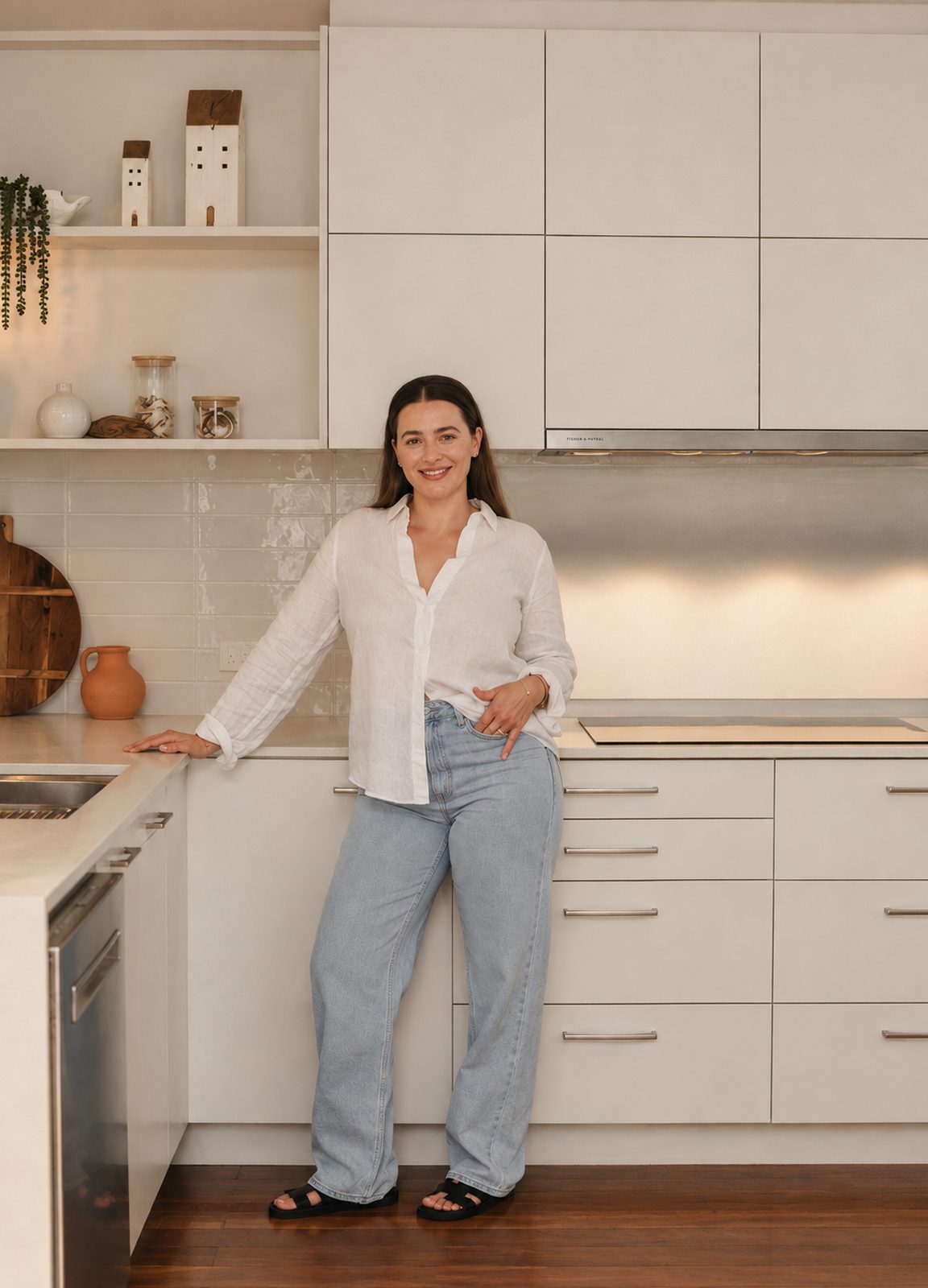 Samantha standing at the bench of a bright white kitchen with timber flooring