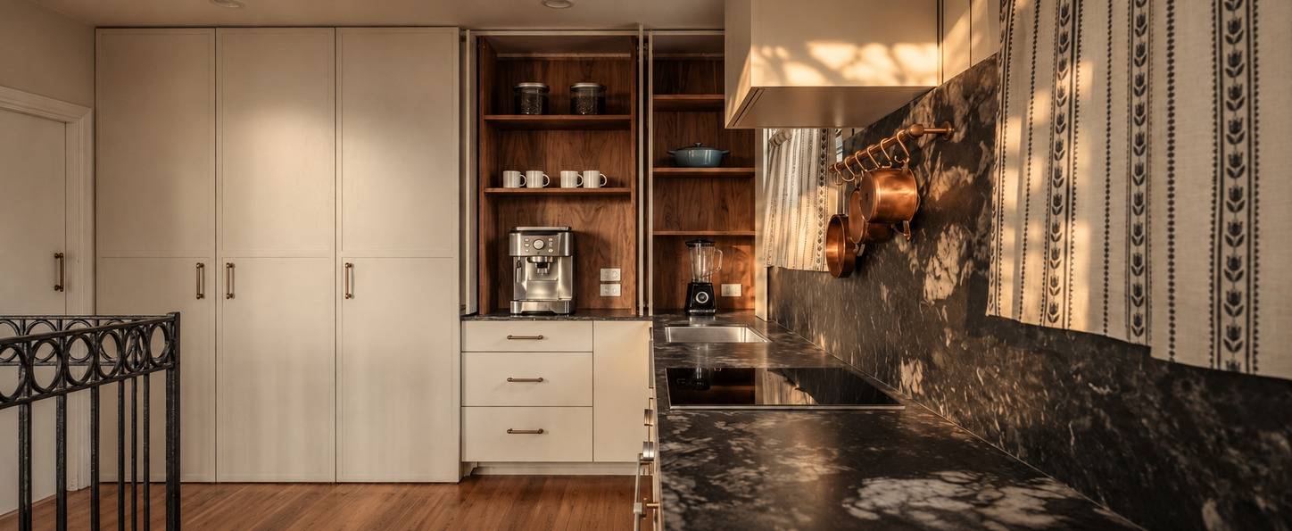Rose Street Kitchen: cream pantry joinery with walnut shelving for the coffee machine and appliances, beneath a floating timber rangehood